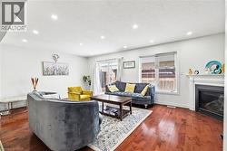 Living area featuring dark wood-style flooring, a glass covered fireplace, a textured ceiling, and recessed lighting - 