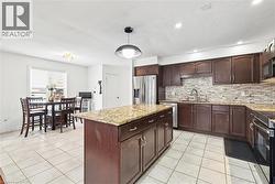 Kitchen with light stone countertops, hanging light fixtures, light tile patterned floors, and a kitchen island - 