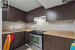 Kitchen featuring stainless steel electric range oven, dark brown cabinets, decorative backsplash, and under cabinet range hood - 