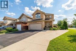 View of front of property featuring brick siding, driveway, a front yard, and an attached garage - 