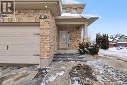Snow covered property entrance with a garage, a porch, stone siding, and brick siding - 