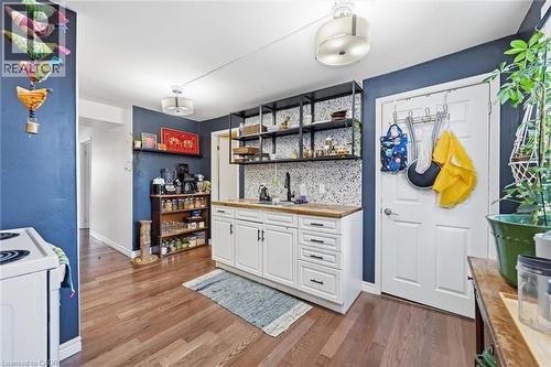 Bar area featuring white cabinetry, open shelves, light wood-style flooring, butcher block counters, and white range with electric stovetop - 18 Fraser Avenue, Hamilton, ON - Indoor