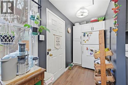 Kitchen with white cabinetry, light wood-style flooring, and freestanding refrigerator - 18 Fraser Avenue, Hamilton, ON - Indoor