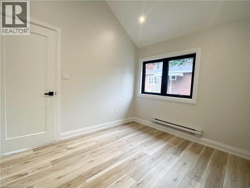 Spare room featuring a baseboard radiator, light wood-style flooring, and lofted ceiling - 110 Deschene Avenue, Hamilton, ON - Indoor Photo Showing Other Room