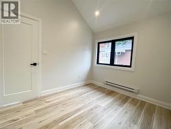 Spare room featuring a baseboard radiator, light wood-style flooring, and lofted ceiling - 