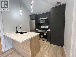 Kitchen with appliances with stainless steel finishes, modern cabinets, a peninsula, light wood finished floors, and backsplash - 