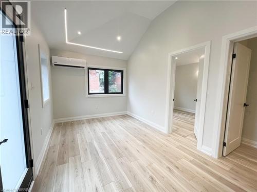 Unfurnished living room with light wood-style flooring, a wall unit AC, high vaulted ceiling, and recessed lighting - 110 Deschene Avenue, Hamilton, ON - Indoor Photo Showing Other Room