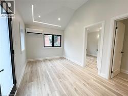 Unfurnished living room with light wood-style flooring, a wall unit AC, high vaulted ceiling, and recessed lighting - 