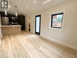 Kitchen with modern cabinets, hanging light fixtures, lofted ceiling, stainless steel appliances, and light wood-type flooring - 