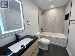 Full bathroom with shower / bath combination, vanity, dark tile patterned flooring, and recessed lighting - 