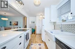 Kitchen with white appliances, white cabinets, pendant lighting, and light wood-type flooring - 