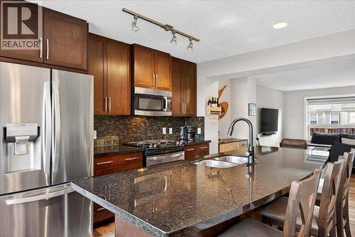 Kitchen island with gas range and slate tile backsplash beyond - 37 Aspen Hills Terrace Sw, Calgary, AB - Indoor Photo Showing Kitchen With Double Sink With Upgraded Kitchen