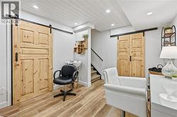Office featuring a barn door, light wood-type flooring, recessed lighting, and wooden ceiling - 