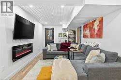 Living area featuring wood finished floors, a glass covered fireplace, recessed lighting, and wood ceiling - 