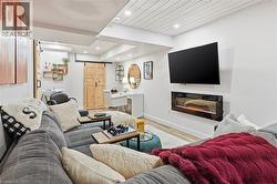 Living room featuring a barn door, wood finished floors, a glass covered fireplace, recessed lighting, and wood ceiling - 