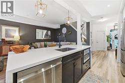 Kitchen with pendant lighting, open floor plan, appliances with stainless steel finishes, light wood-style floors, and dark cabinetry - 