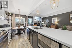 Kitchen featuring a chandelier, open floor plan, stainless steel appliances, pendant lighting, and dark cabinets - 