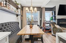 Dining space with a glass covered fireplace, light wood-style floors, and a chandelier - 