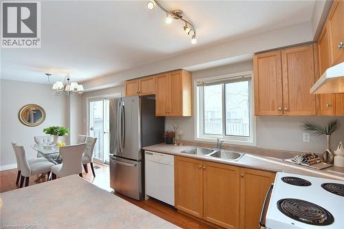 Kitchen with white appliances, light countertops, light wood-style floors, a chandelier, and healthy amount of natural light - 2258 Empire Crescent, Burlington, ON - Indoor Photo Showing Kitchen With Double Sink