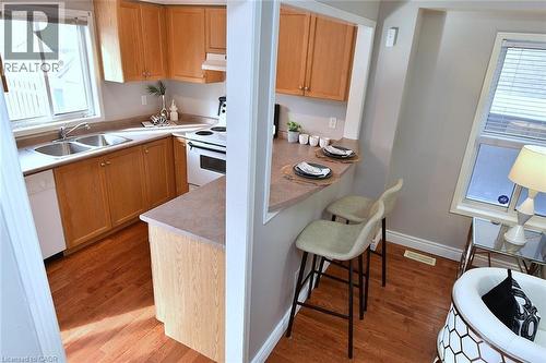 Kitchen featuring a kitchen bar, light wood-type flooring, light countertops, and white appliances - 2258 Empire Crescent, Burlington, ON - Indoor Photo Showing Kitchen With Double Sink