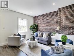 Living area with an accent wall, wood finished floors, brick wall, visible vents, and recessed lighting - 