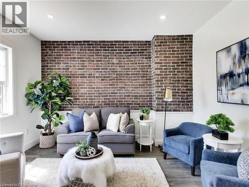 Living area with baseboards, wood finished floors, recessed lighting, brick wall, and an accent wall - 54 Fairview Avenue, Hamilton, ON - Indoor Photo Showing Living Room