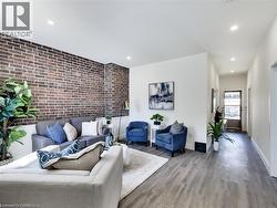 Living room with baseboards, brick wall, an accent wall, and wood finished floors - 