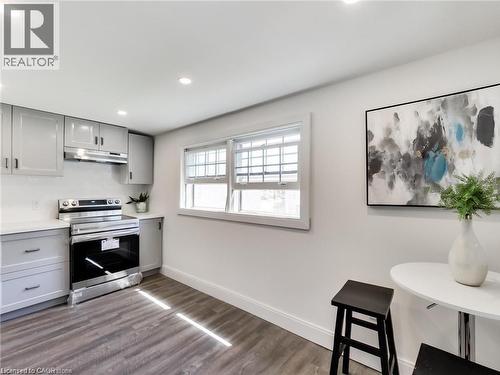 Kitchen featuring electric stove, gray cabinetry, under cabinet range hood, and baseboards - 54 Fairview Avenue, Hamilton, ON - Indoor Photo Showing Kitchen