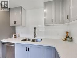 Kitchen with light countertops, tasteful backsplash, a sink, and dishwasher - 