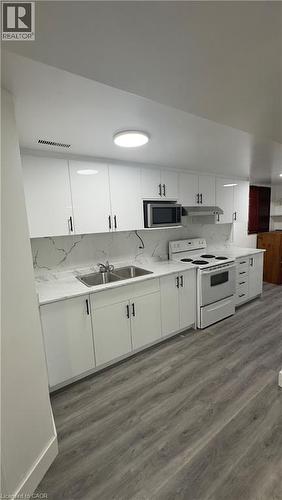 Kitchen with white cabinetry, white electric stove, and light wood-type flooring - 18 Ingleside Drive, Kitchener, ON - Indoor Photo Showing Kitchen With Double Sink