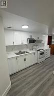Kitchen with white cabinetry, white electric stove, and light wood-type flooring - 