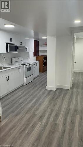 Kitchen with white cabinets, white range with electric cooktop, light countertops, light wood-style floors, and stainless steel microwave - 18 Ingleside Drive, Kitchener, ON - Indoor Photo Showing Kitchen