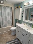 Full bath featuring vanity, shower / bath combination with curtain, and light tile patterned floors - 