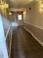 Corridor featuring dark tile patterned flooring, a decorative wall, a baseboard heating unit, wainscoting, and a textured ceiling - 