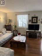 Living room with wood finished floors, a textured ceiling, and a baseboard radiator - 