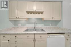 Kitchen featuring light countertops, dishwasher, and white cabinets - 