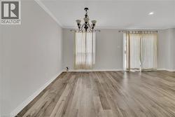 Unfurnished dining area with a chandelier, crown molding, and light wood-type flooring - 
