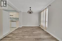 Unfurnished dining area with crown molding, a chandelier, and light wood-style flooring - 
