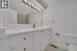 Bathroom featuring light marble finish flooring, vanity, and tiled shower - 