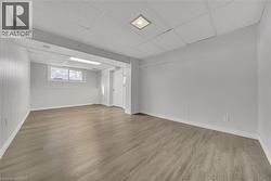 Basement with a paneled ceiling, light wood-type flooring, and wood walls - 