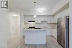 Kitchen with stainless steel appliances, under cabinet range hood, light wood-type flooring, and a sink - 