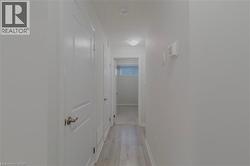 Corridor with a textured ceiling, light wood finished floors, and baseboards - 