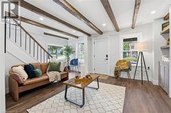 Living room with stairs, beamed ceiling, dark wood-style flooring, and recessed lighting - 