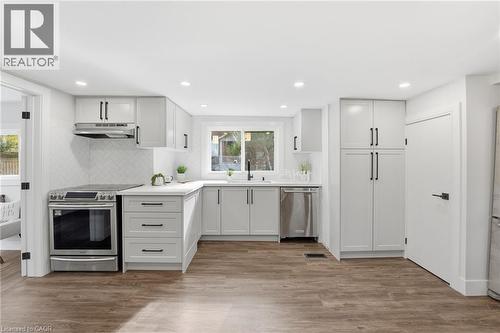 Kitchen with decorative backsplash, stainless steel appliances, white cabinets, light wood-style floors, and recessed lighting - 4255 William Street, Beamsville, ON - Indoor Photo Showing Kitchen With Upgraded Kitchen