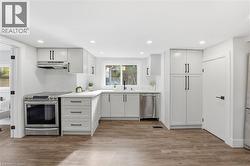 Kitchen with decorative backsplash, stainless steel appliances, white cabinets, light wood-style floors, and recessed lighting - 