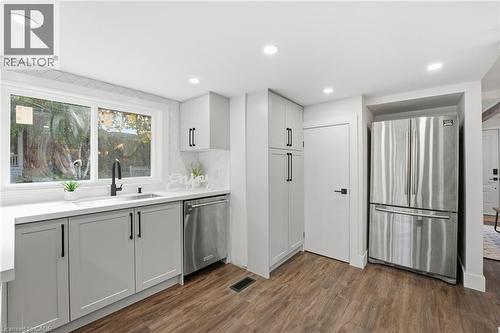 Kitchen featuring appliances with stainless steel finishes, dark wood-style flooring, recessed lighting, decorative backsplash, and white cabinets - 4255 William Street, Beamsville, ON - Indoor Photo Showing Kitchen
