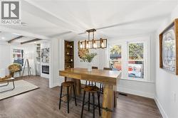 Dining area with beamed ceiling, wood finished floors, a glass covered fireplace, and a chandelier - 