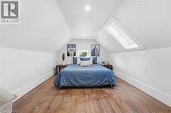 Bedroom featuring lofted ceiling, wood finished floors, a skylight, and recessed lighting - 