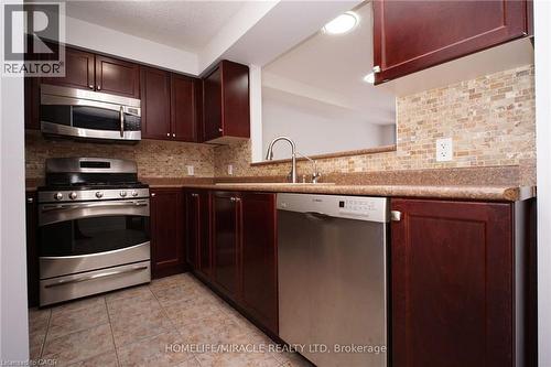 Kitchen with appliances with stainless steel finishes, decorative backsplash, light tile patterned floors, and dark brown cabinetry - 919 Zeller Crescent, Kitchener, ON - Indoor Photo Showing Kitchen