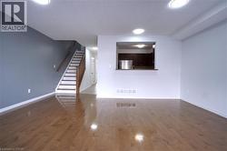 Unfurnished living room with stairs, dark wood-style flooring, and recessed lighting - 
